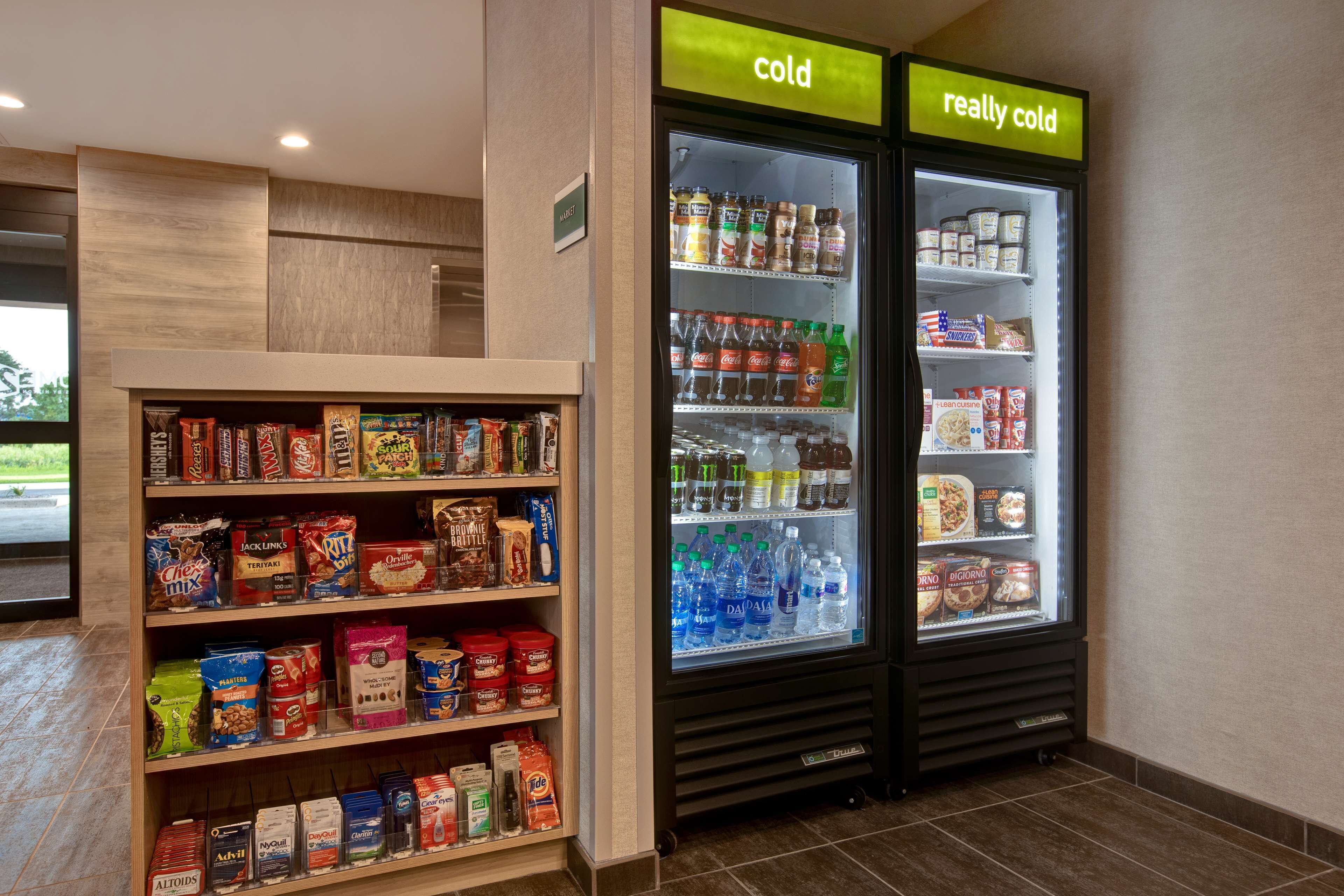 A refrigerated display with various food items and a shelf stocked with snacks and cereals.