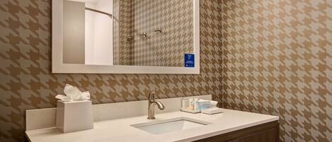 A bathroom with a mirror, sink, towel rack, and toiletries.