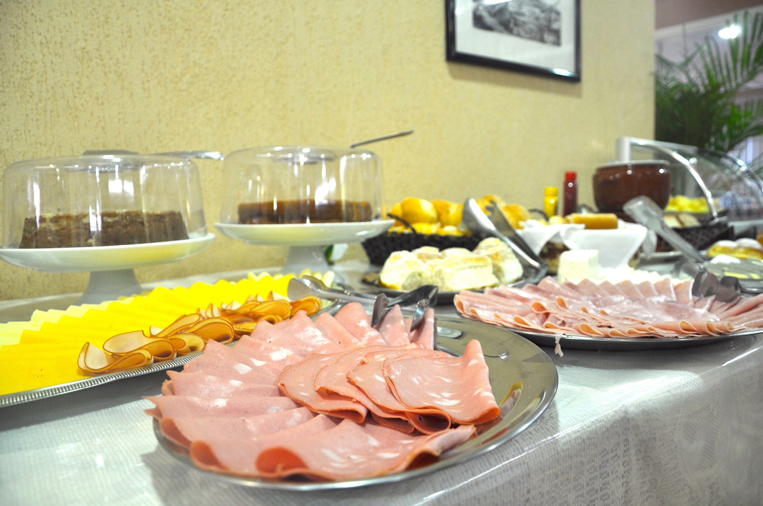 Una mesa de buffet con diversos alimentos, como carnes frías, frutas y bebidas.