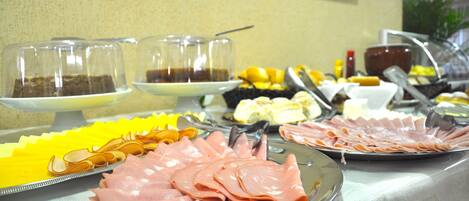 Una mesa de buffet con diversos alimentos, como carnes frías, frutas y bebidas.