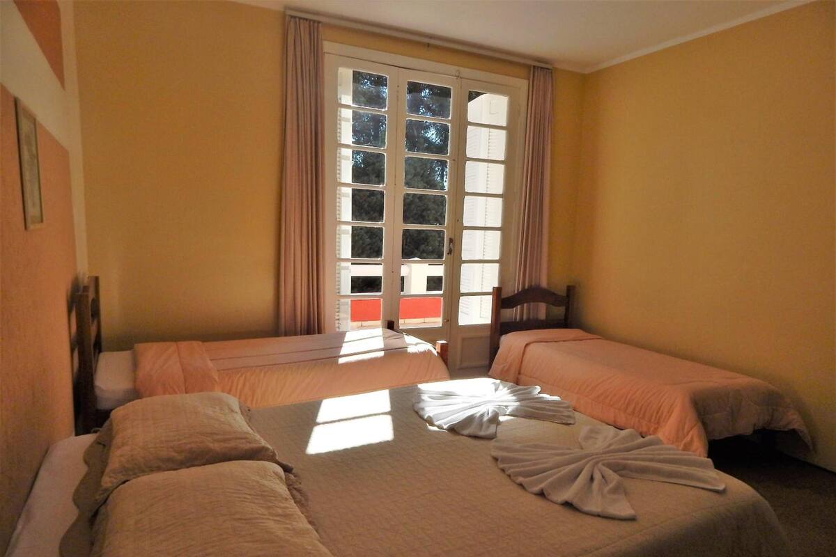 Habitación de hotel con dos camas, un ventanal grande y vistas al exterior.