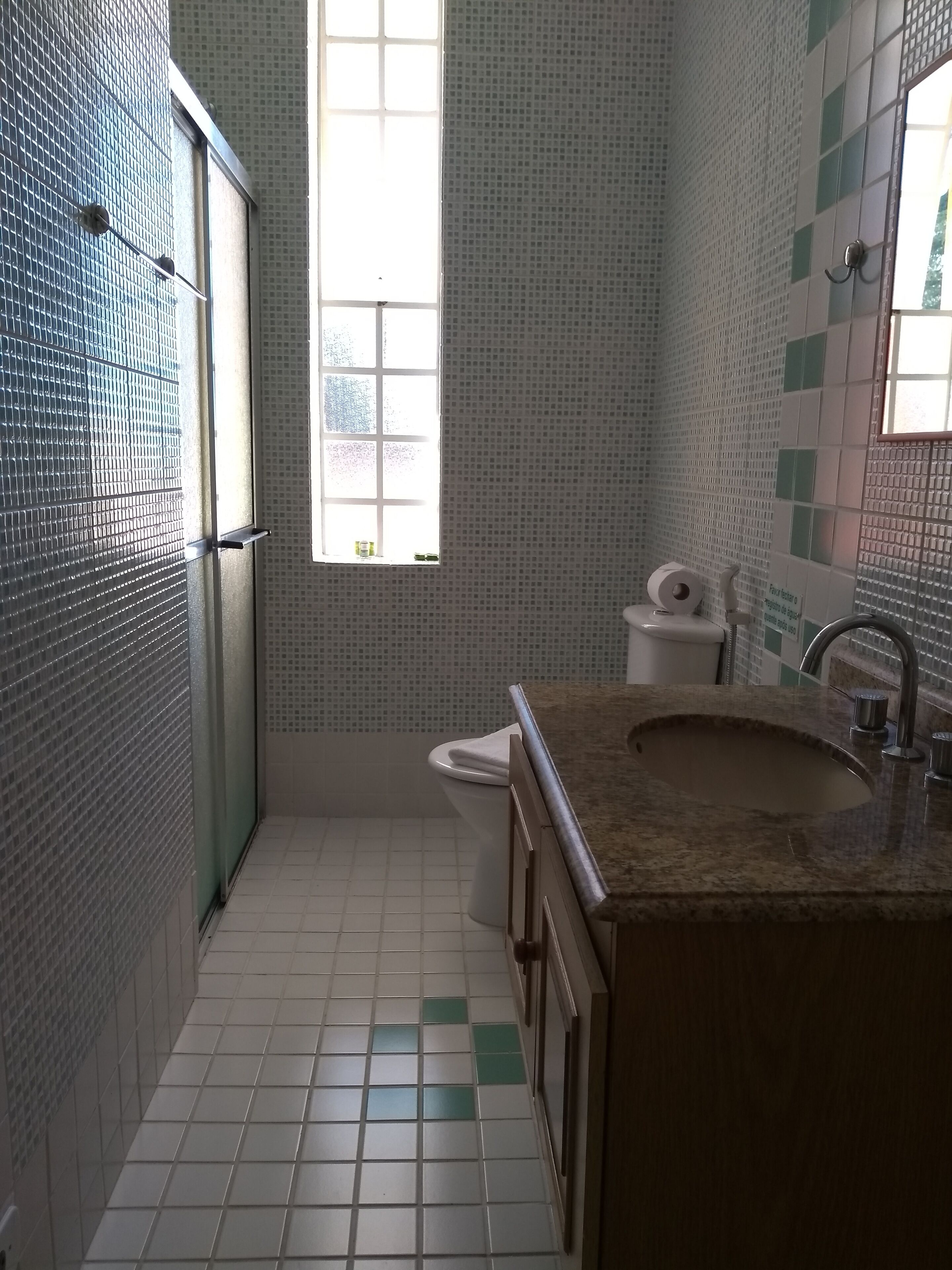A small bathroom with a window, a sink, and a toilet.