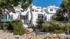 A coastal residential area with white buildings, stone walls, and greenery. - Air-Conditioned Holiday Apartment "Bungalow Cala Dor 27" with Sea View and Pool (Cala D'or)