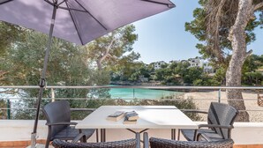An outdoor patio with a table, chairs, and an umbrella. - Air-Conditioned Holiday Apartment "Bungalow Cala Dor 27" with Sea View and Pool (Cala D'or)