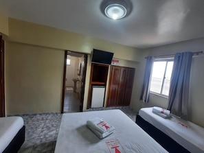 A hotel room with two beds, a television, a wardrobe, and a window with curtains. - Hotel Central (Belém)