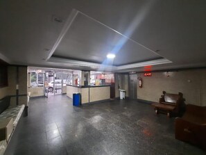 A spacious lobby with a reception desk, a trash bin, and a fire extinguisher on the wall. - Hotel Central (Belém)