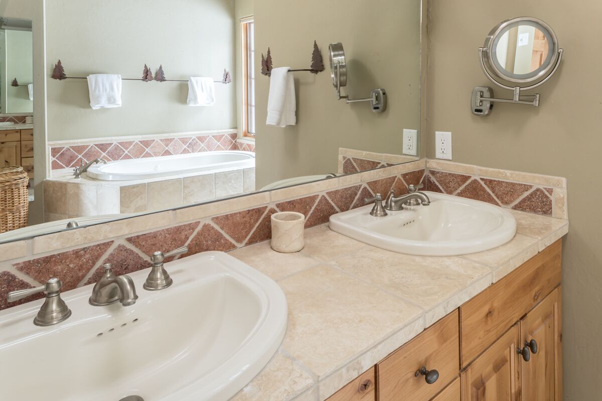 A bathroom with two sinks, a mirror, and a towel rack.