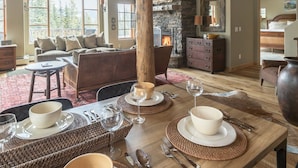 Uma sala de jantar com uma mesa de madeira posta para quatro pessoas, rodeada por individuais de palha e tigelas.