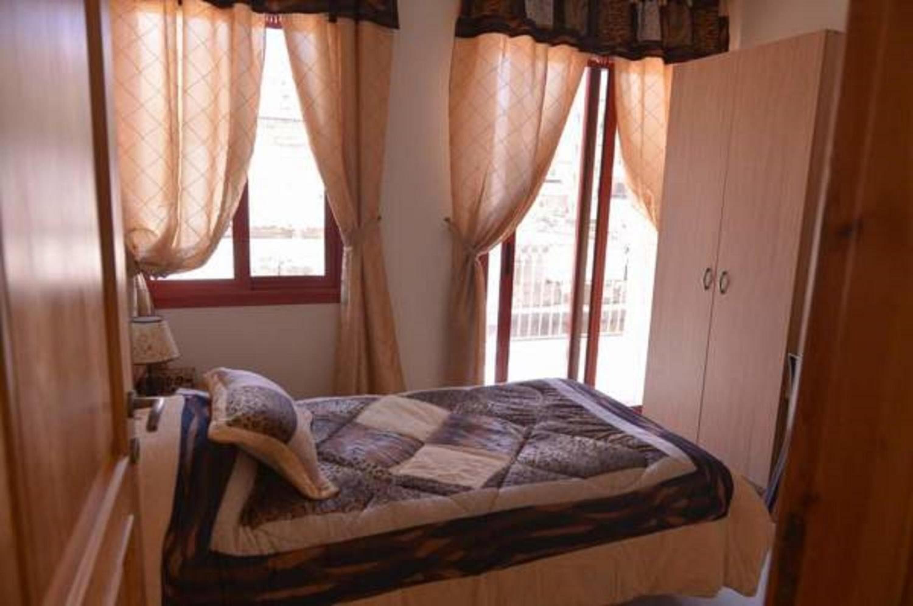 A bedroom with a bed, curtains, and a window.