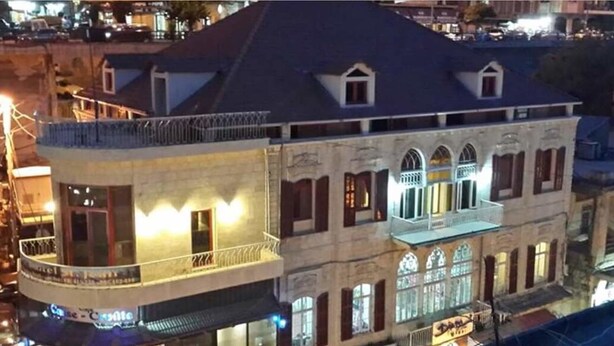 A multi-story building with a balcony on the ground floor, large windows, and a sign that reads "Hotel". - Hôtel Saint Jean Zahle (Zahlé)