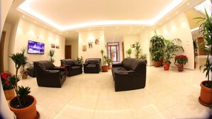 A spacious living area with a high ceiling, multiple seating arrangements, and potted plants. - Hôtel Saint Jean Zahle (Zahlé)