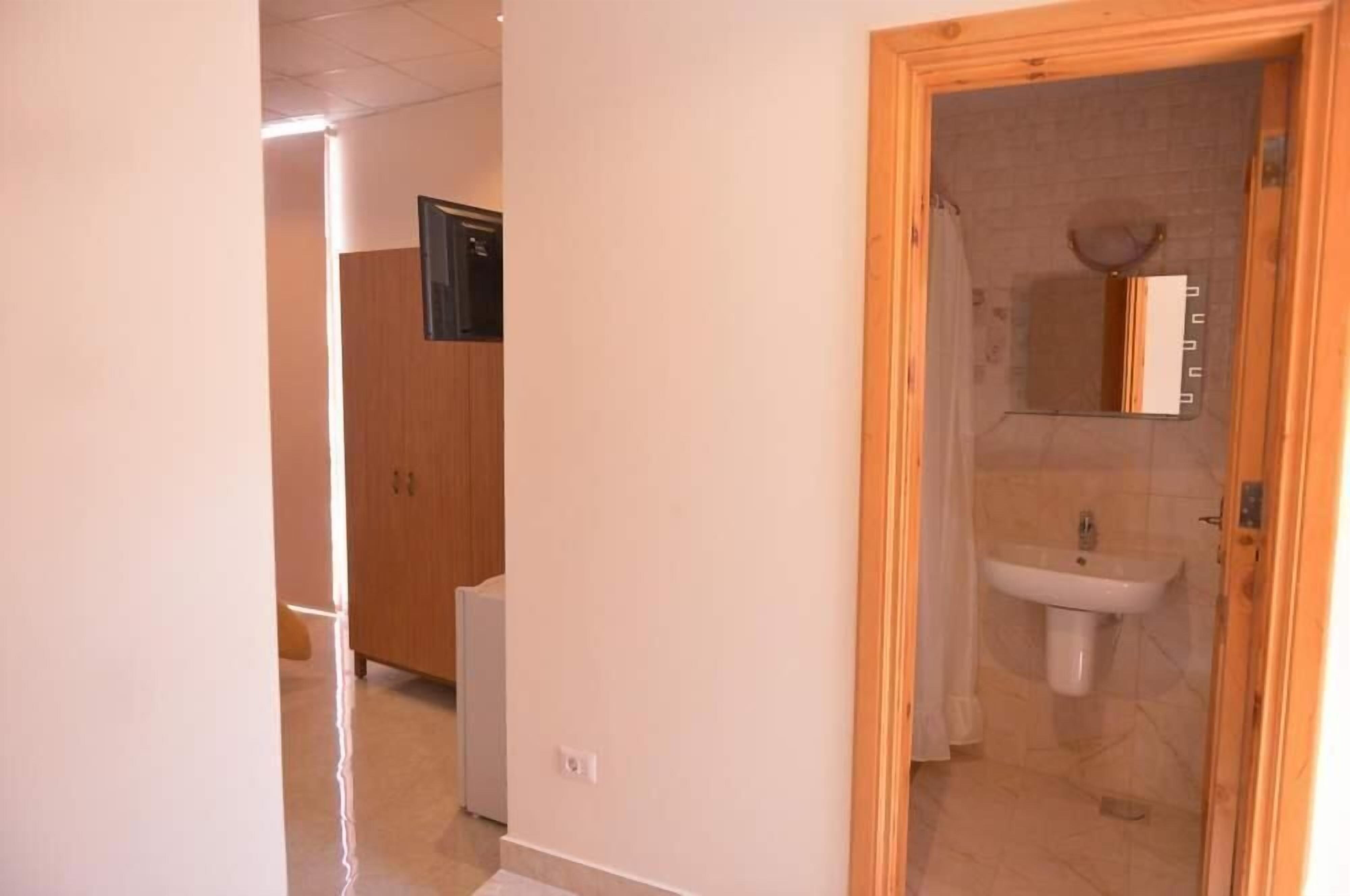 Un baño con lavabo y espejo, armarios de madera y zona de ducha.