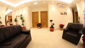 A hotel lobby with two sofas, potted plants, and a wooden door. - Hôtel Saint Jean Zahle (Zahlé)