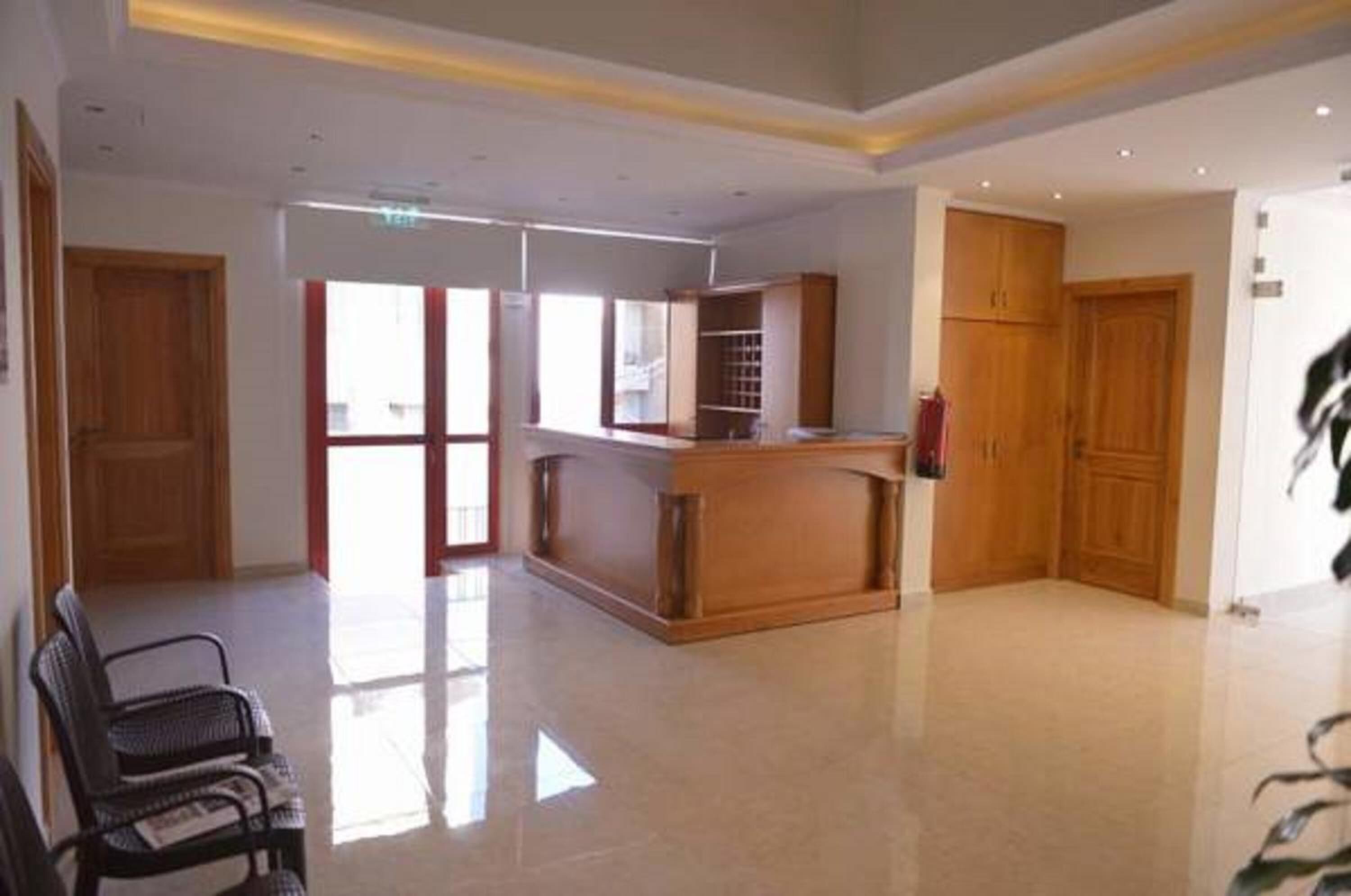 A spacious lobby with a reception desk, wooden cabinets, and a bench.