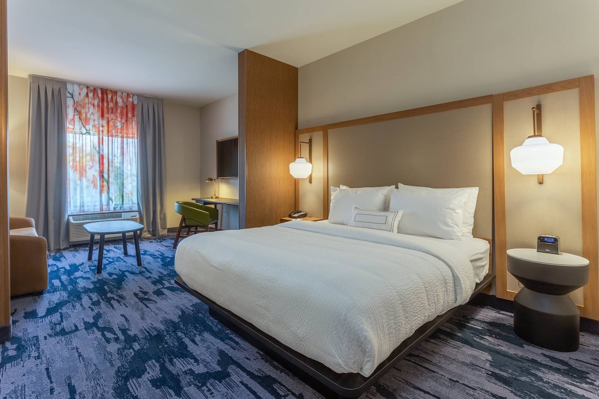 Een hotelkamer met een groot bed, een bureau, een stoel en een klein tafeltje.