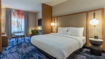 A hotel room with a large bed, a desk, a chair, and a small table.