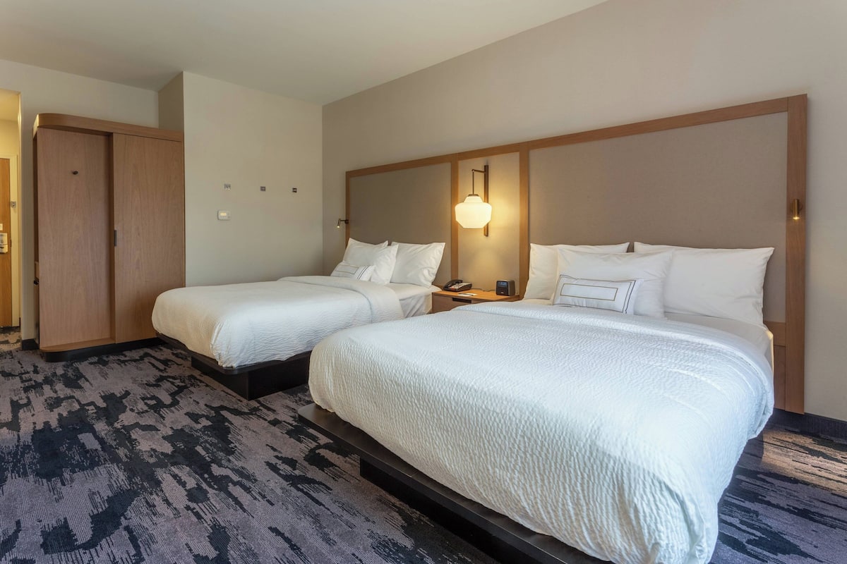 Een hotelkamer met twee bedden, een kledingkast en een vloerbedekking.