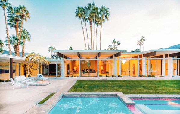 A modern house with a swimming pool, outdoor seating, and palm trees. - Famous Pink Door | Pool | Billiard Room (Palm Springs)
