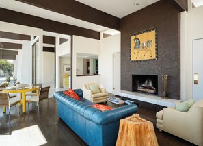 A modern living room with a blue sofa, a white armchair, and a fireplace. - Famous Pink Door | Pool | Billiard Room (Palm Springs)