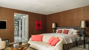 Una camera da letto moderna con un letto grande, un divano, un tavolino da caffè e un quadro astratto rosso sulla parete.