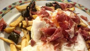 Un plat de menjar amb patates fregides, un ou de sol i carn.