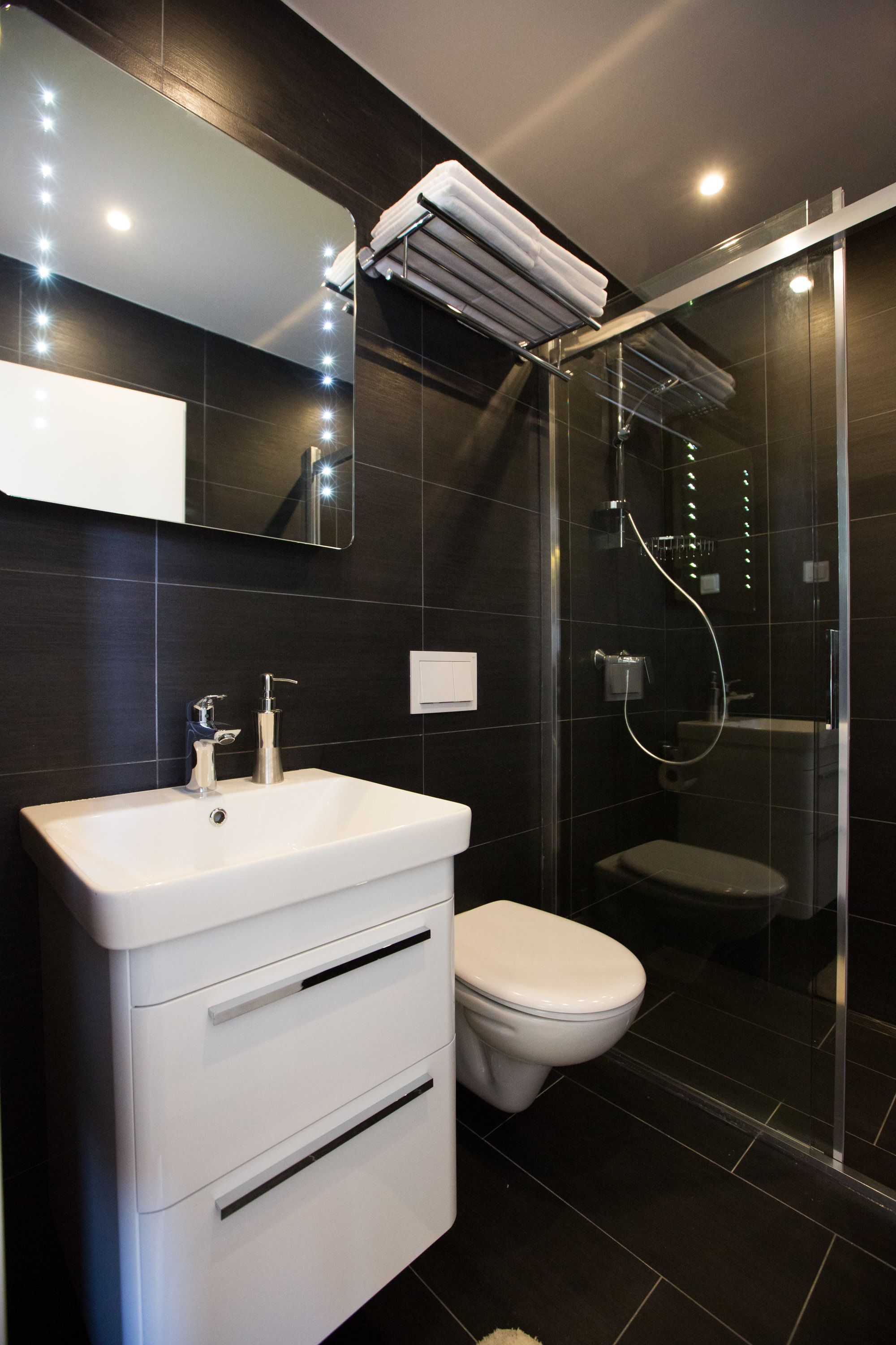 Casa de banho moderna com toucador branco, sanita e cabine de duche com vidro.