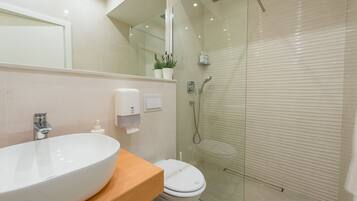 A modern bathroom with a large oval sink, a toilet, and a glass-enclosed shower.