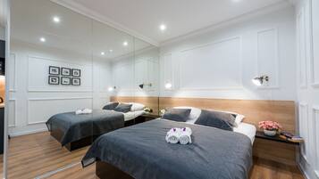 Una camera d'albergo con due letti, un grande specchio e un comodino con un vaso di fiori.