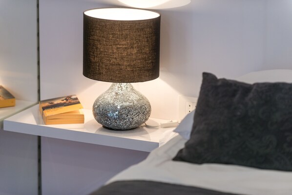 A bedside table with a lamp, a book, and a decorative item. - Scalini Palace (Dubrovnik)