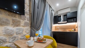 A modern kitchen with a built-in microwave, a sink, and a flat-screen TV mounted on a stone wall. - Scalini Palace (Dubrovnik)