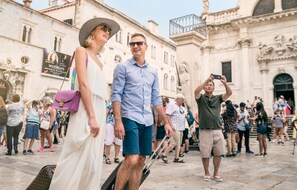 A historic building with classical architecture, a public square, and people walking. - Scalini Palace (Dubrovnik)