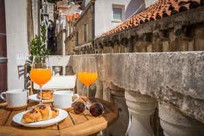 A table with a croissant, two glasses of orange juice, and a pair of sunglasses. - Scalini Palace (Dubrovnik)