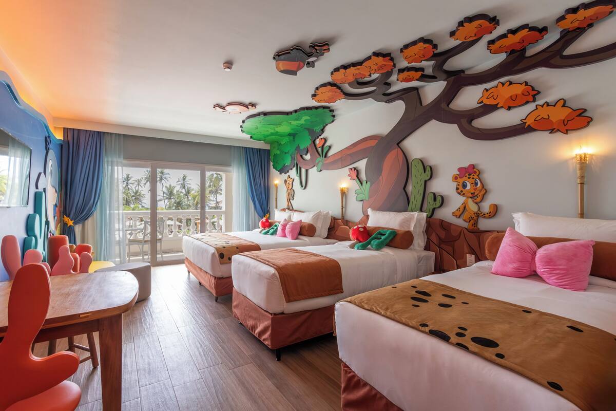 Habitación de hotel con dos camas, un comedor y un balcón con vistas.