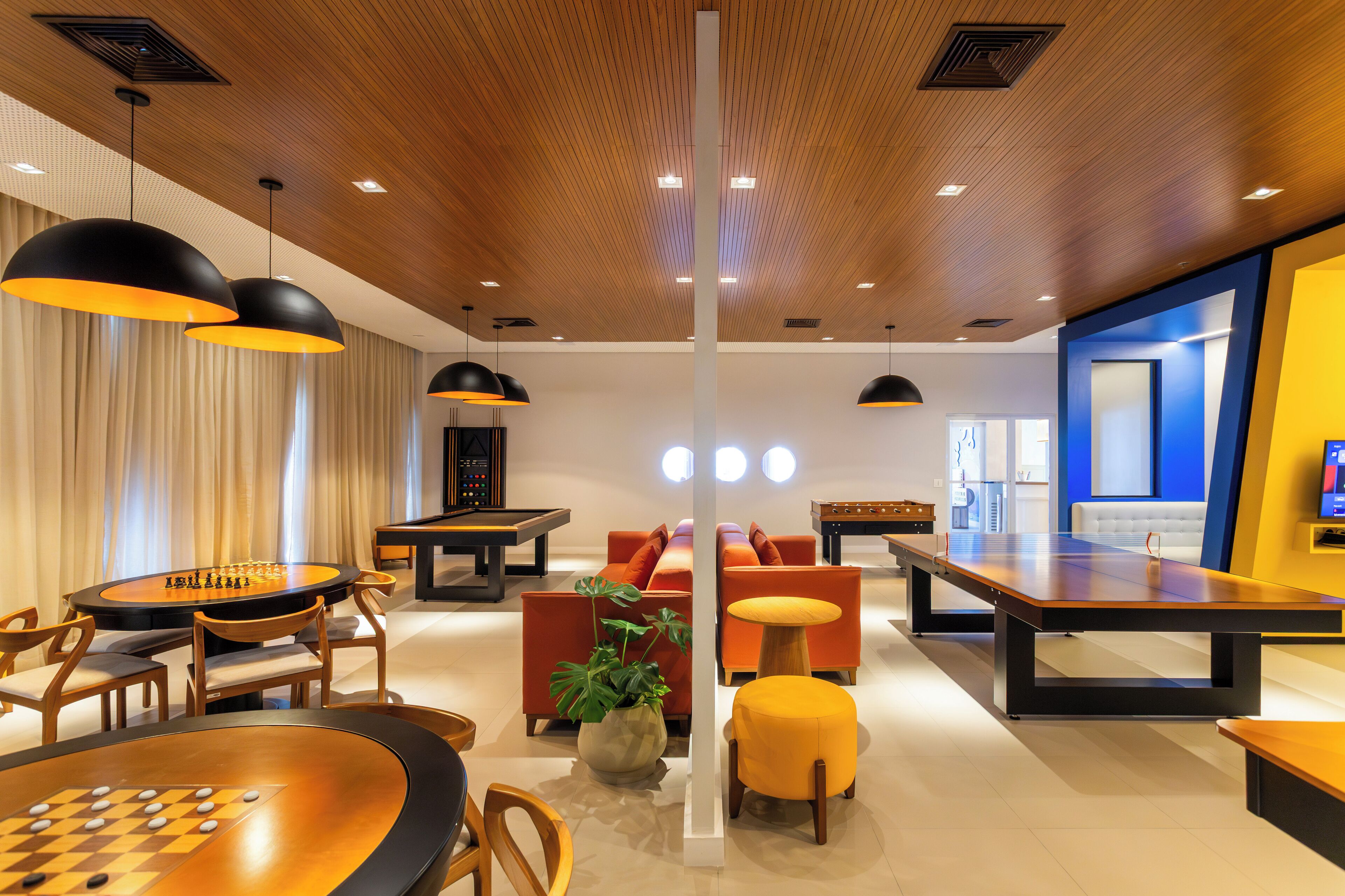 A modern lounge area with a pool table, comfortable seating, and a large table for games.