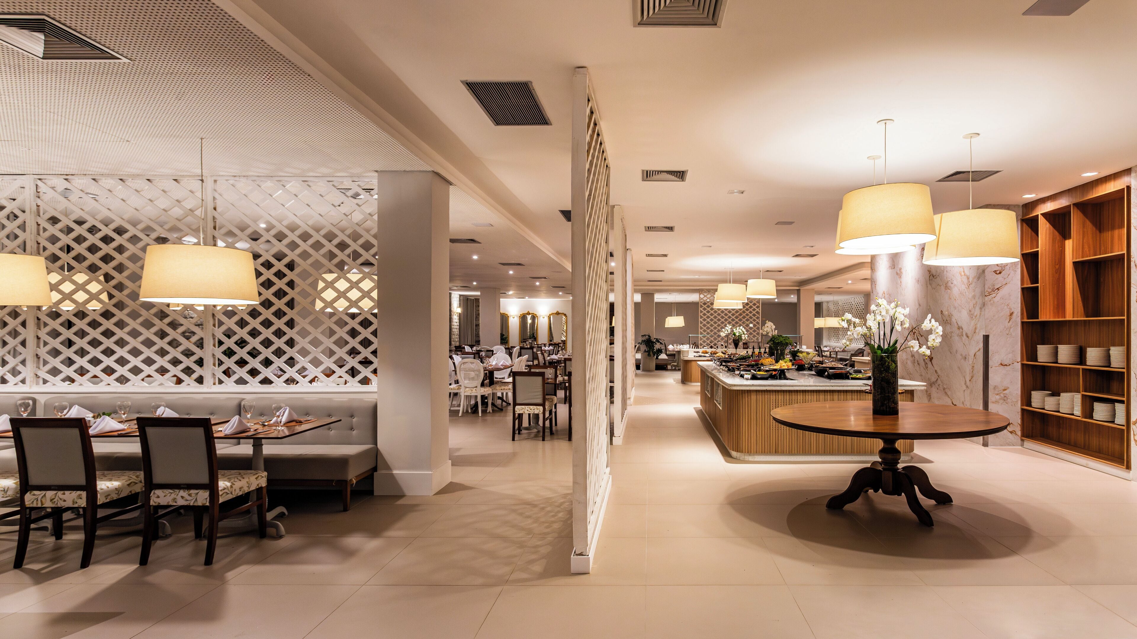 A modern hotel lobby with a central seating area, a reception desk, and a buffet.