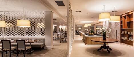 A modern hotel lobby with a central seating area, a reception desk, and a buffet.