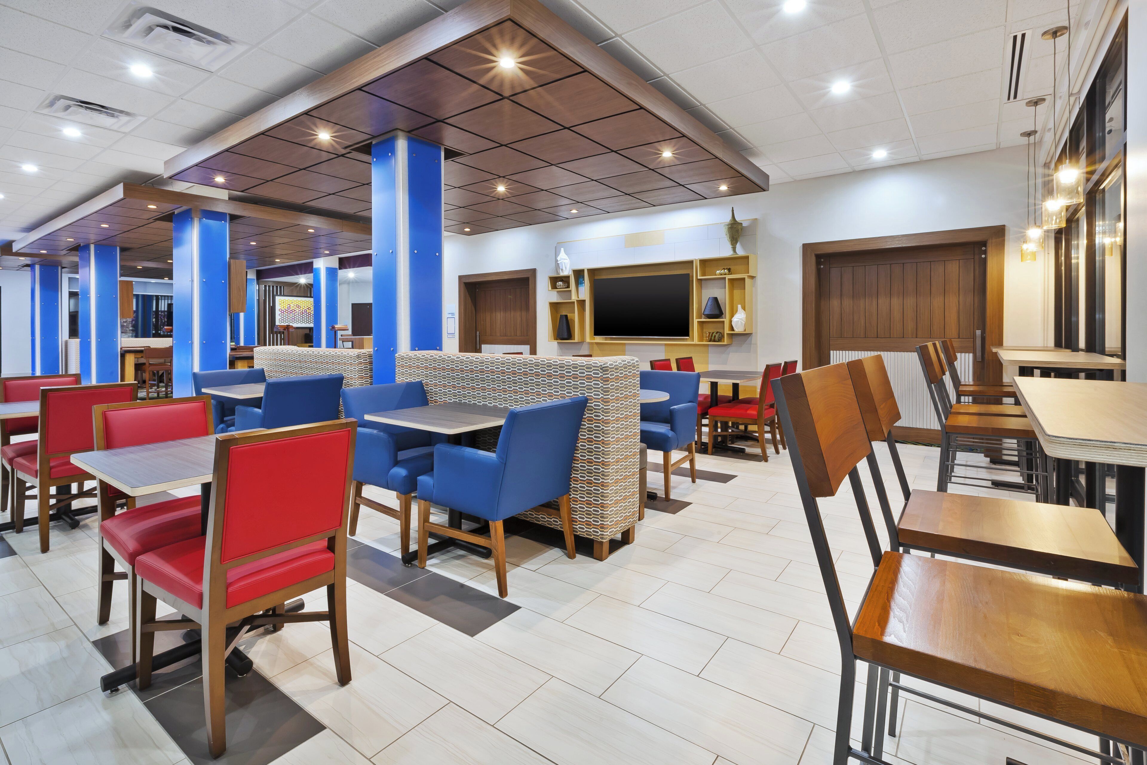 Un restaurante con cabinas y mesas, un televisor de pantalla plana y una pared con diseño.
