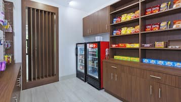 Ein Bereich für Snacks und Getränke mit Regalen voller verschiedener Marken, einem Kühlschrank und einem Holzkabinet.