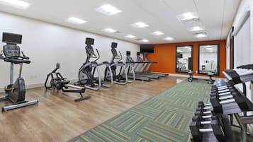 Academia com esteiras, bicicletas ergométricas e remo.