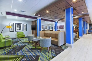 A lobby with a sofa, chairs, a patterned carpet, and artwork on the walls. - Holiday Inn Express & Suites Painesville - Concord by IHG (Painesville)