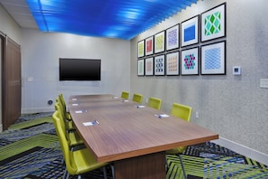 A conference room with a long table, yellow chairs, a flat-screen TV, and framed geometric art on the wall. - Holiday Inn Express & Suites Painesville - Concord by IHG (Painesville)