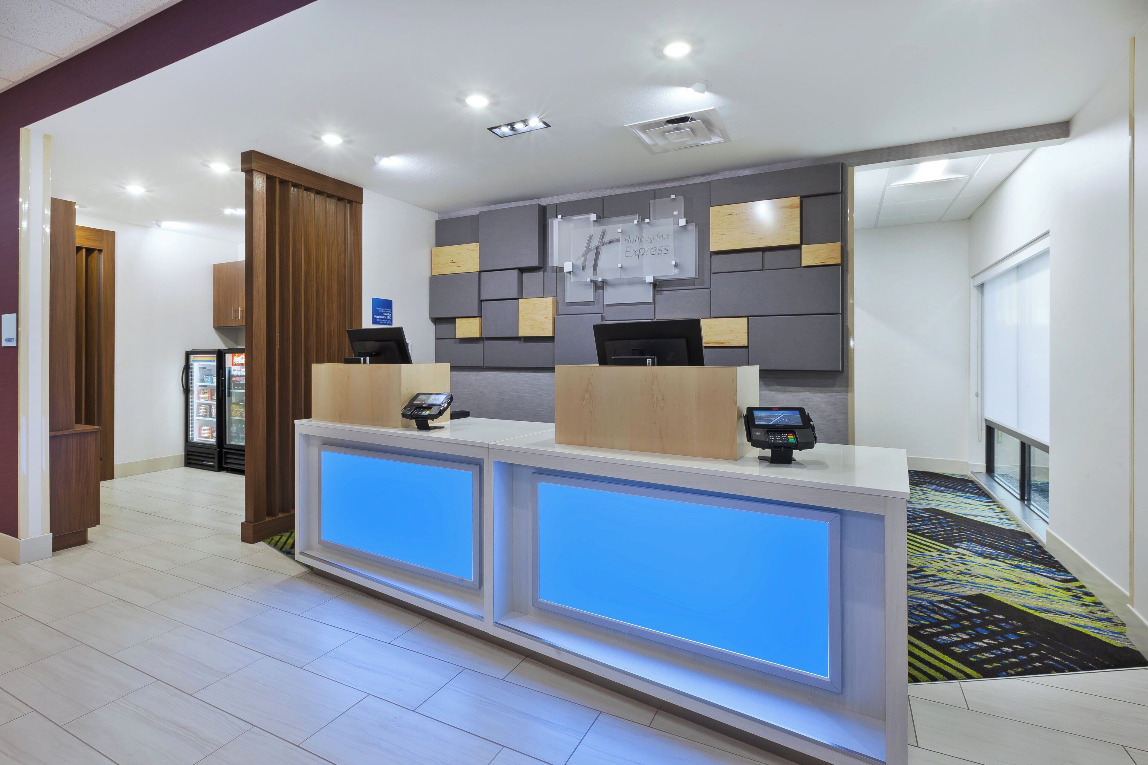 A hotel reception desk with a modern design, a digital display, and a counter with a cash register.