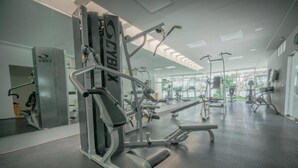 A gym with various exercise machines, a mirrored wall, and a large window providing natural light. - Xaman 201   by NAS (Playa del Carmen)