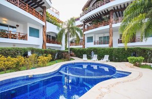 Un hôtel doté d’une piscine centrale, de nombreux balcons et d’une végétation luxuriante.