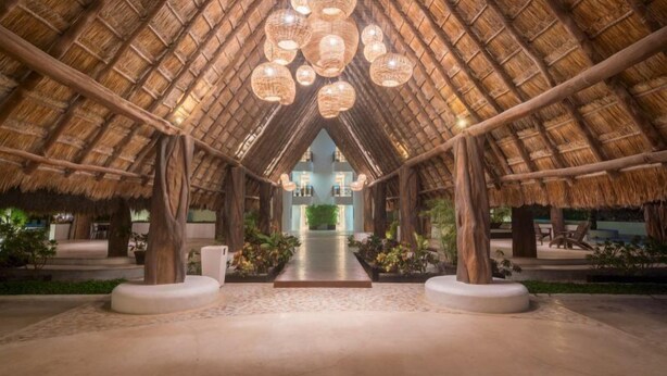 An interior with a thatched roof, a central pathway, and seating areas. - Xaman 201   by NAS (Playa del Carmen)