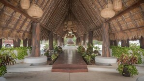 A covered walkway with a thatched roof, leading to a central area with hanging light fixtures. - Xaman 201   by NAS (Playa del Carmen)