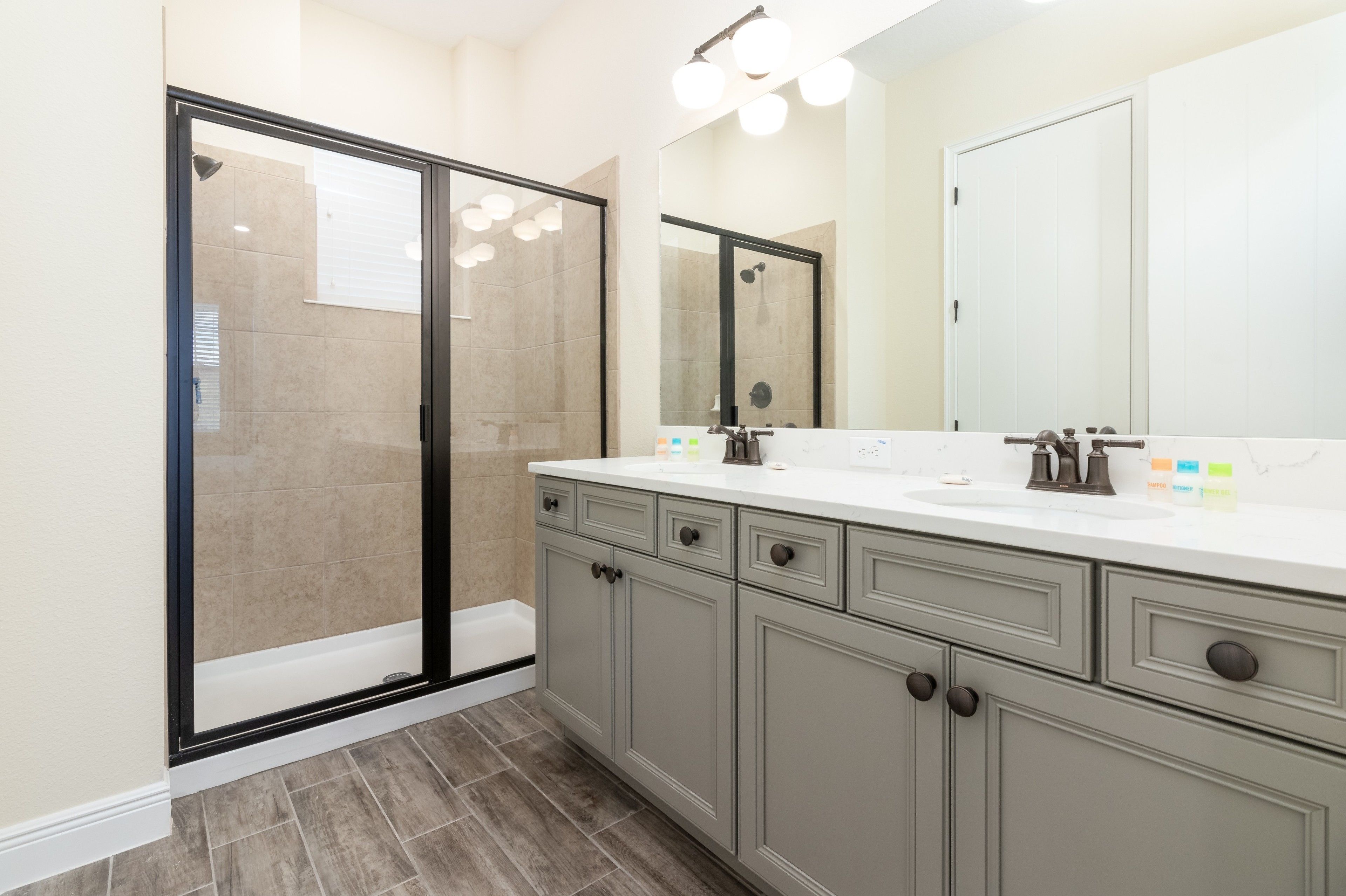 Un bagno moderno con cabina doccia in vetro, uno specchio grande e un mobile lavabo con lavandino e cassetti contenitori.