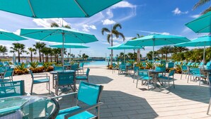 Un espace aménagé au bord de la piscine, avec des parasols turquoise, des chaises longues et une vue dégagée sur la piscine.