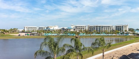 A resort with a large building, a lake, and palm trees.