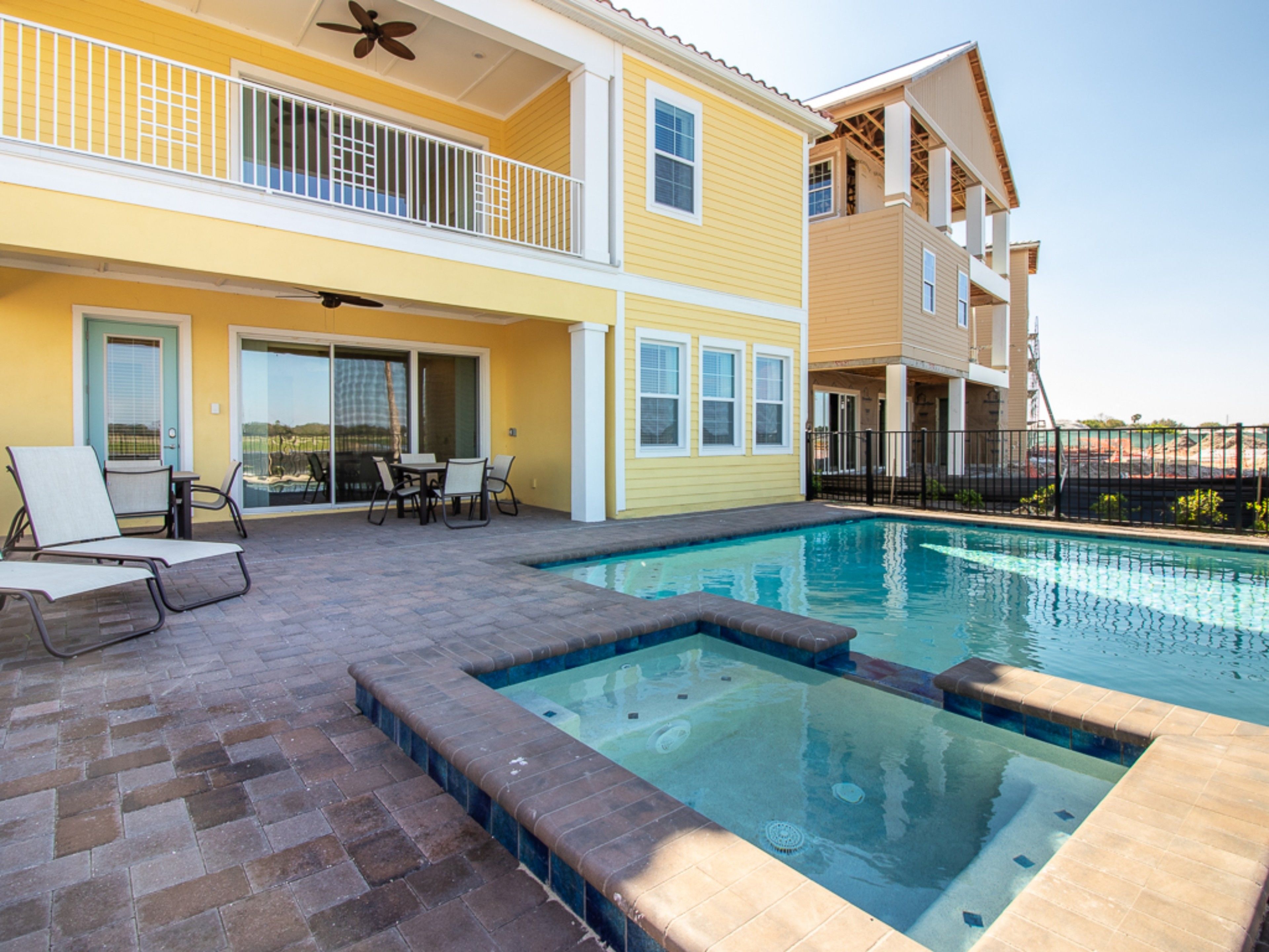 A two-story building with a swimming pool, outdoor seating, and a covered patio area.